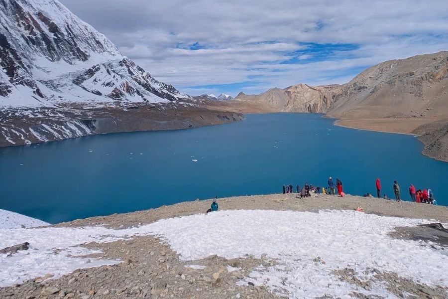 Tilicho Lake surrounded by barren mountains with trekkers viewing
